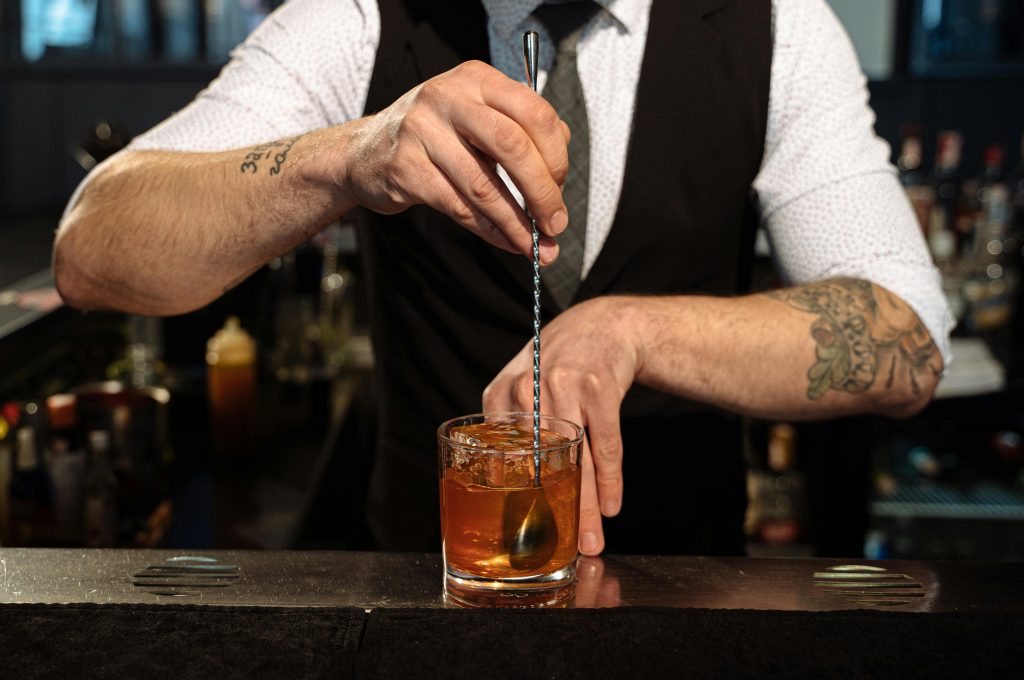 A bartender expertly blends a cocktail with ice, showcasing professional skills and style.