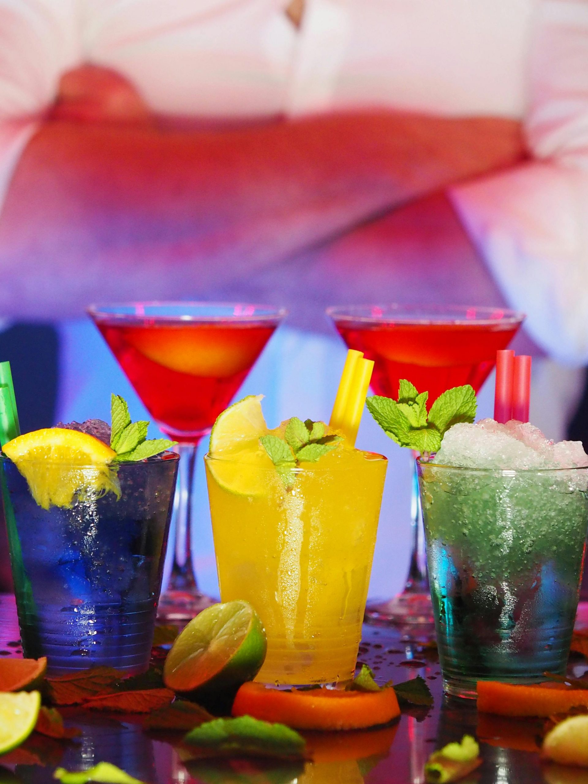 Colorful cocktails with citrus slices on a bar, perfect for nightlife settings.